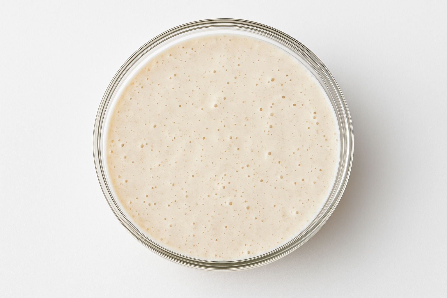 Glass bowl with risen dough on a white background